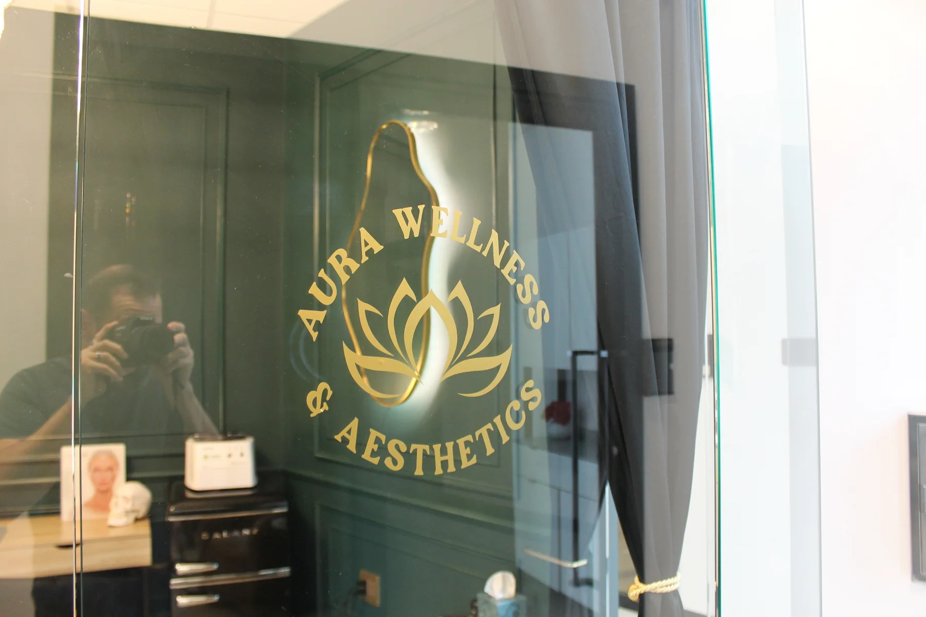 Aura Wellness & Aesthetics gold logo etched on the glass of Suite 118