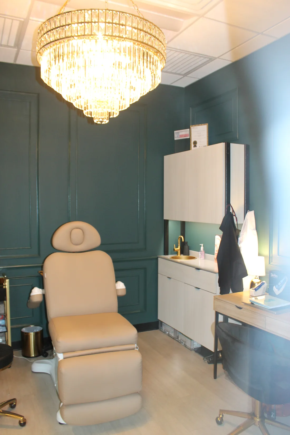 Aura Wellness Suite 118 treatment room — luxury medspa with crystal chandelier, emerald walls, and premium treatment chair
