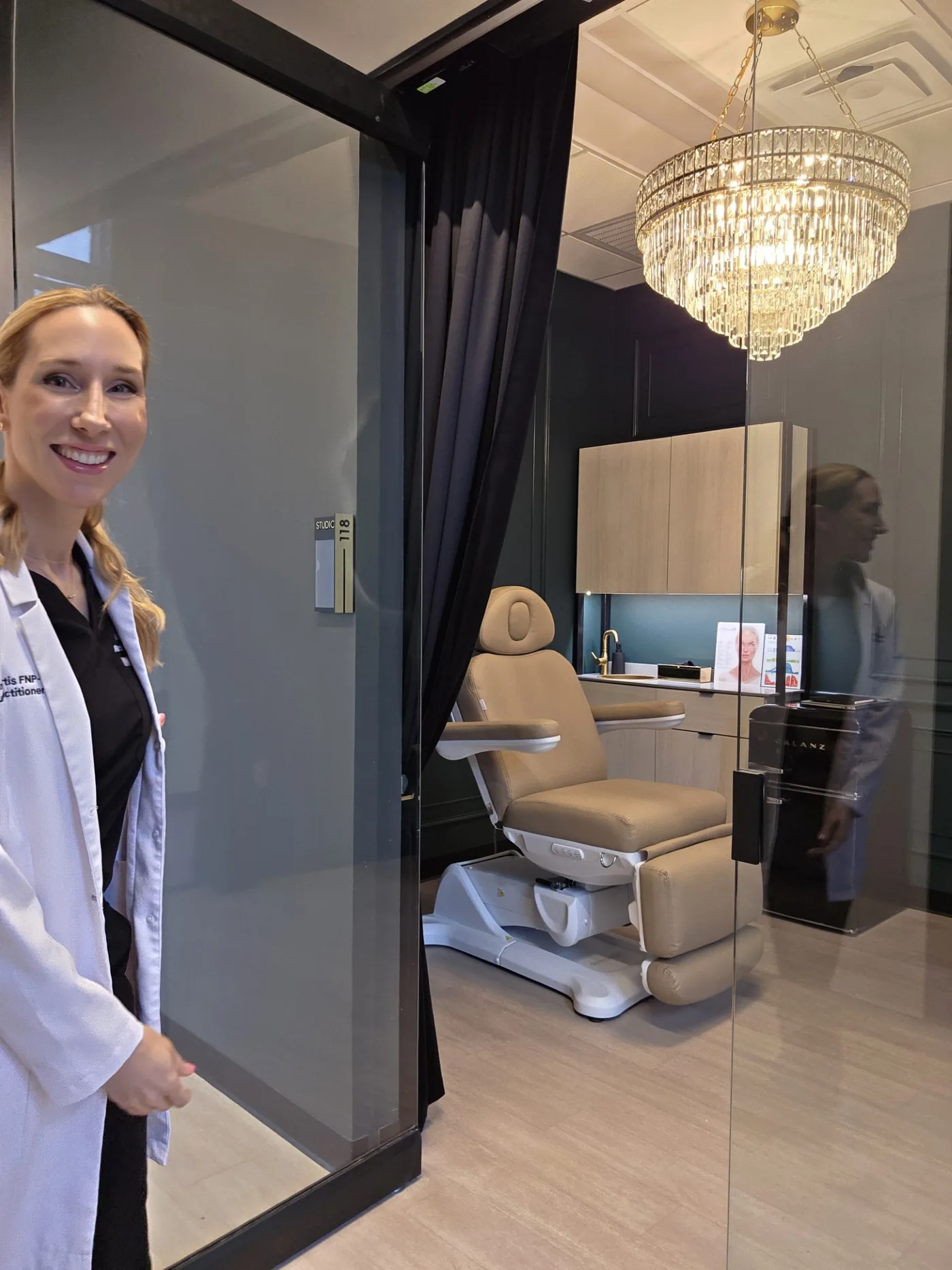 Amanda welcoming a guest at the open door of Aura Wellness & Aesthetics, Suite 118